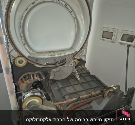 פנים של מייבש כביסה פתוח עם תוף ומנוע חשמלי